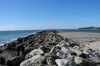 The southern arm of the jetty during low tide shows the sand build-up (sand dunes) inside the harbor on the right and the open water on the left that leads to Surfer's Beach. (Rosemary Mena-Werth/Peninsula Press)
