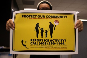 A rapid responder trainee holds a yellow poster with the words "PROTECT OUR COMMUNITY, REPORT ICE ACTIVITY! CALL (408) 290-1144" and an image of a family walking.