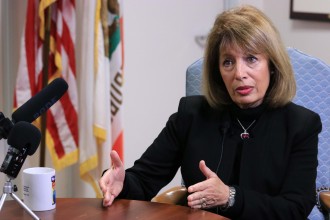 A woman talks in front of a mic and recorder.