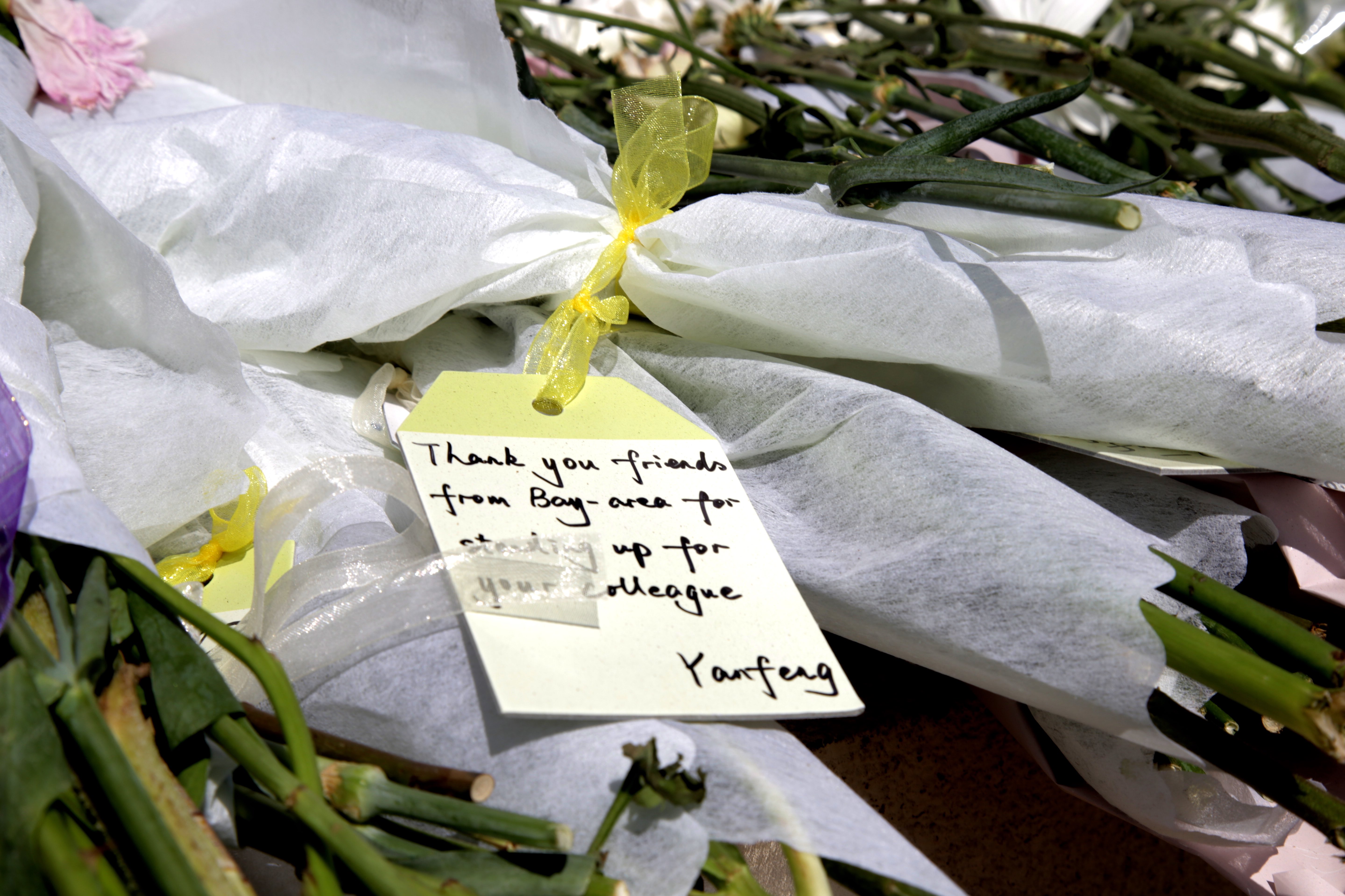 Flowers are brought to the scene on Thursday September 26, 2019 by protestors who express their condolences and honor the passing of Qin Chen. One of the cards, written by a protestor named Yanfeng, says, “Thank you friends from Bay Area for standing up for your colleague.”  (Qian Chen/Peninsula Press)