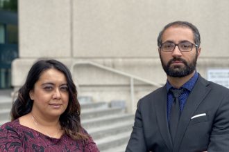 Charlene Mahabali and Alen Yaghoubi stand in front of the stairs and a sign for the Santa Clara County Main Jail at 150 West Hedding Street in San Jose