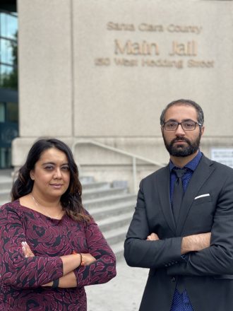 Charlene Mahabali and Alen Yaghoubi stand in front of the stairs and a sign for the Santa Clara County Main Jail at 150 West Hedding Street in San Jose