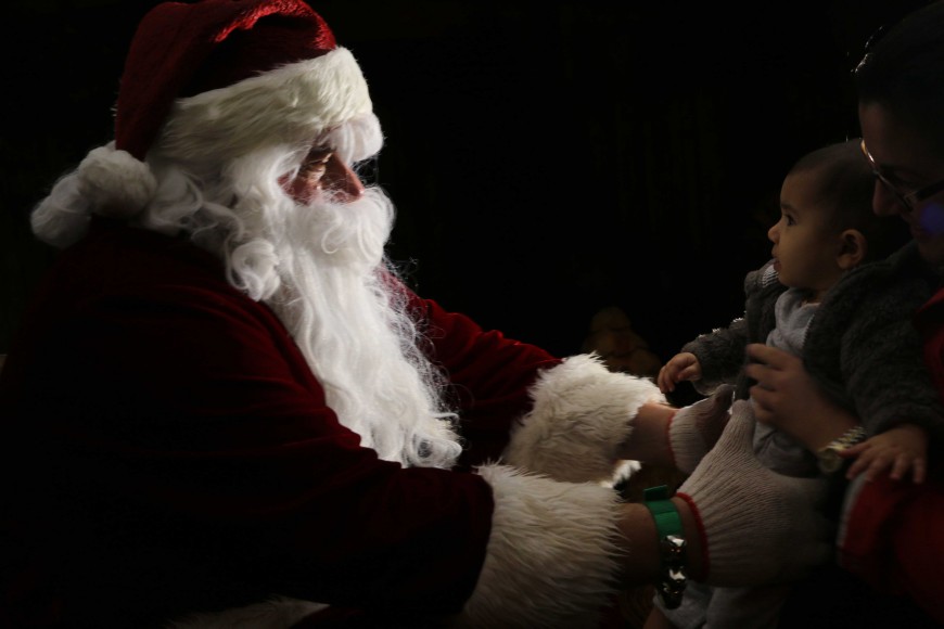 Santa eagerly reaches to embrace six-month-old Morgan Chabra. (Phoebe Barghouty/Peninsula Press)