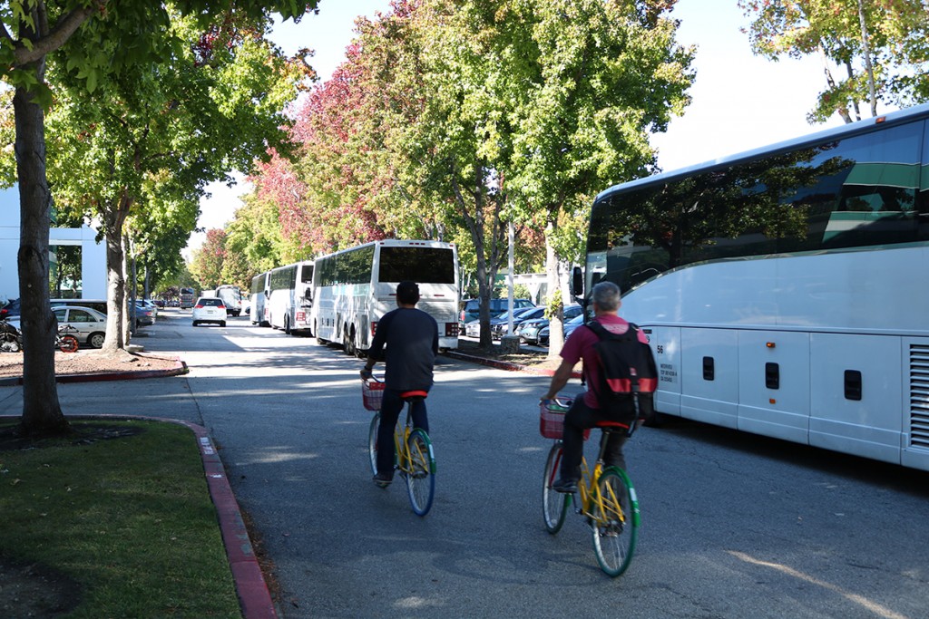 Two Google employees on “G-Bikes” are passing a line of shuttle busses, Oct. 21, 2016. Both the “G-Bikes” and Google’s shuttle buses have helped to bring some traffic relief to Mountain View, the city’s Vice Mayor Ken Rosenberg said. (Felix Petermann/Peninsula Press)