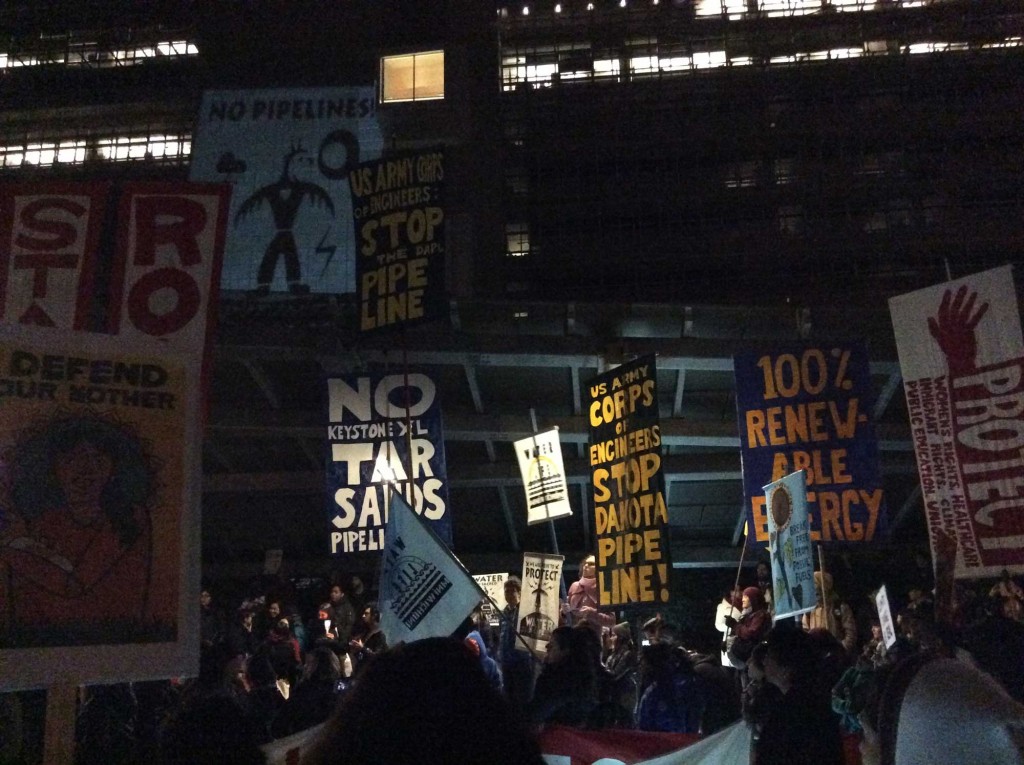 A crowd of at least two thousand stands before the walls of the San Francisco Federal Building, illuminated by NoDAPL art projections. (Natasha Mmonatau/Peninsula Press) 