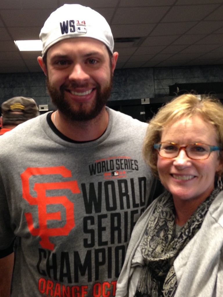 Joan Ryan and San Francisco Giants first baseman Brandon Belt pose in the Giants clubhouse after the team's victory in the 2014 World Series. (Photo courtesy of Joan Ryan)