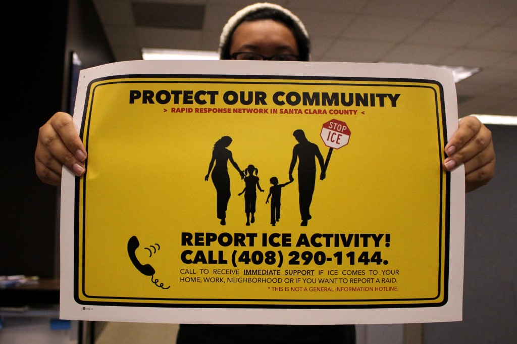 A rapid responder trainee holds a yellow poster with the words "PROTECT OUR COMMUNITY, REPORT ICE ACTIVITY! CALL (408) 290-1144" and an image of a family walking.