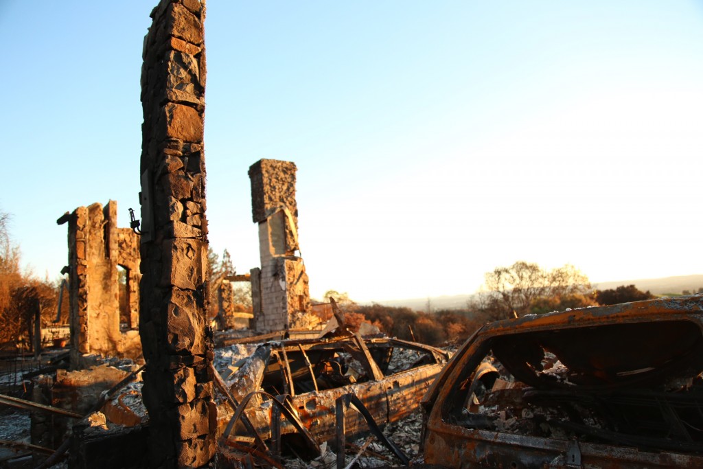 Skeletons of cars and fireplaces emerge amid fire rubble in the upscale neighborhood of Fountaingrove at sunset.