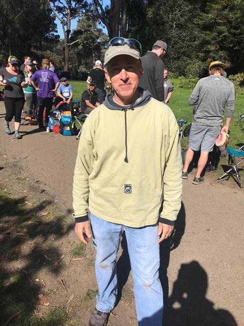 A man looking at the camera is standing at the Golden Gate Park Disc Golf Course