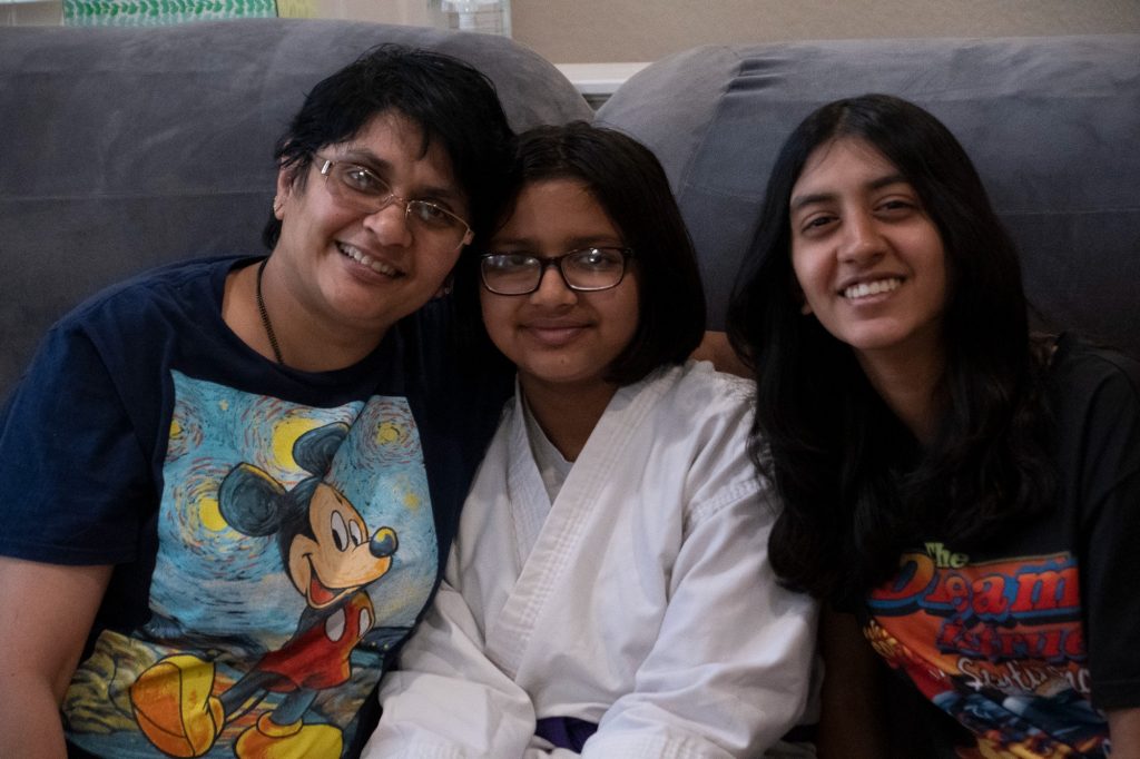 A mother and her two daughters smile at the camera.