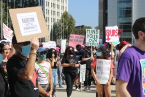 Protesters walk together holding up signs.