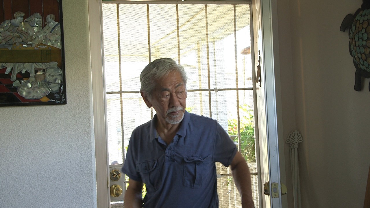 Fred Kameda is pictured inside his home with the front door behind him.
