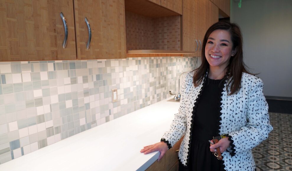 Betty Duong, manager of the Vietnamese American Service Center, poses in front of the building's food pantry. Its bamboo cabinets were designed with traditional basket weave motif paneling, another aesthetic nod to Vietnamese culture and tradition. (Elissa Miolene/Peninsula Press)
