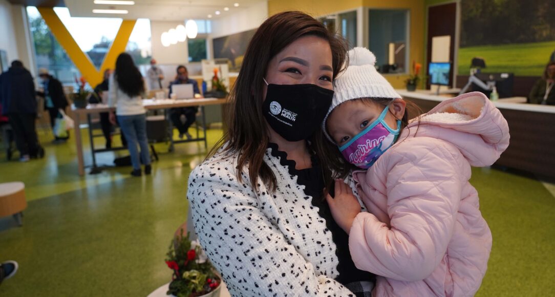 Betty Duong, manager of the new Vietnamese American Service Center, holds her 4-year-old daughter Harper at the soft launch on Monday, December 13. (Elissa Miolene/Peninsula Press)
