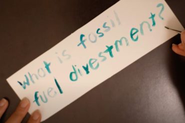 A hand writing out 'What is fossil fuel divestment?'