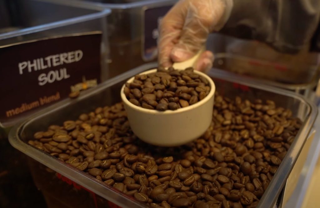 A hand scooping up coffee beans