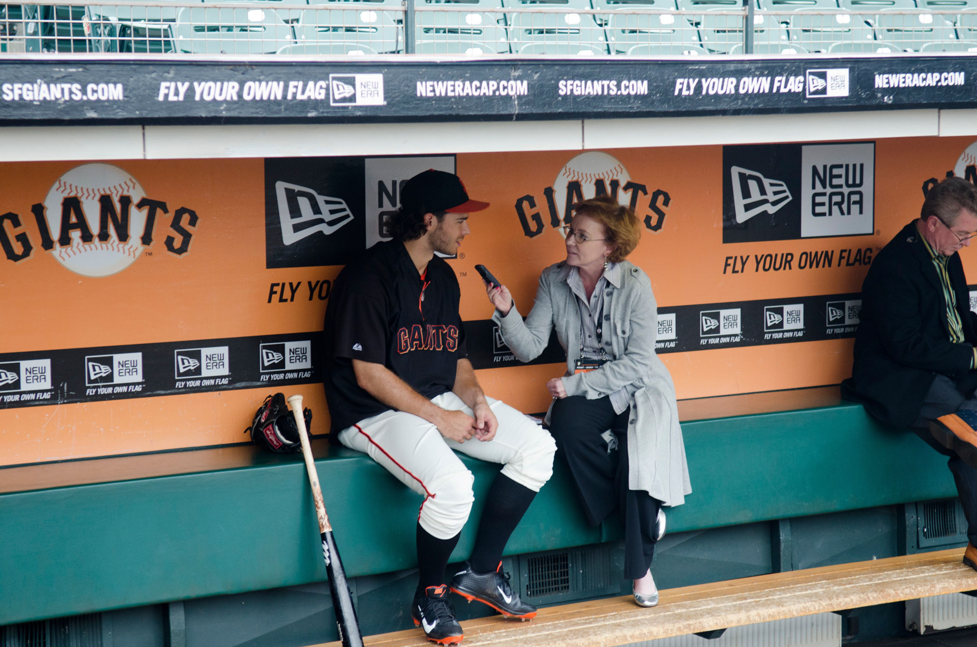 A woman interviews a San Francisco Giants baseball player in the dugout.