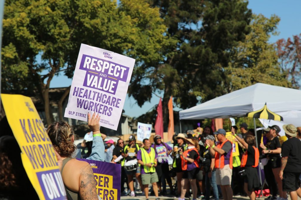 Workers hold up signs.
