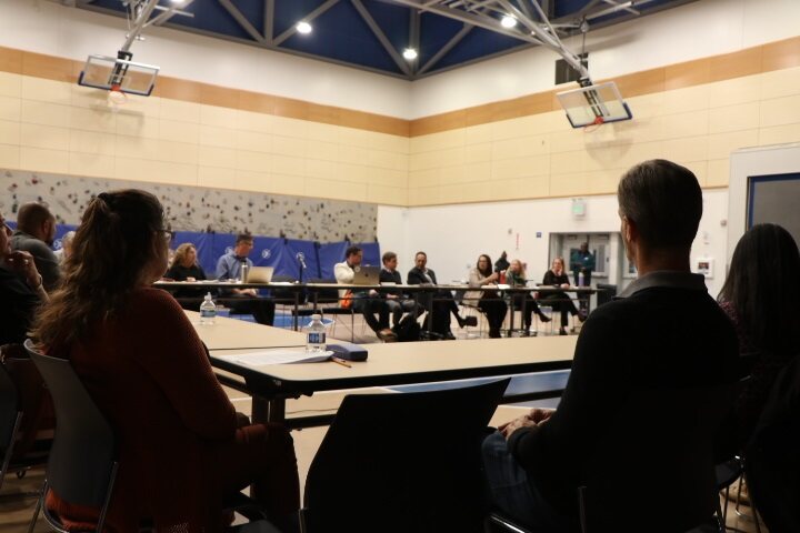 People gathered around several tables facing one another.