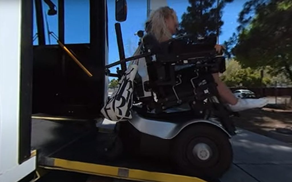 A wheelchair user gets off of a bus.