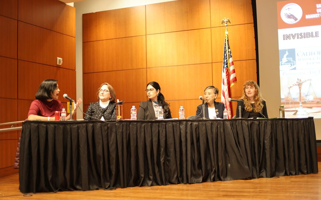 Five people sit behind a table during a panel.