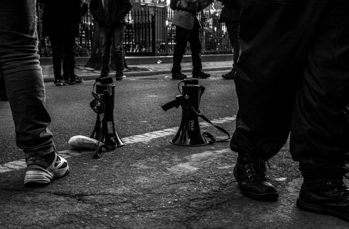 Two megaphones are on the street surrounded by the feet of protesters